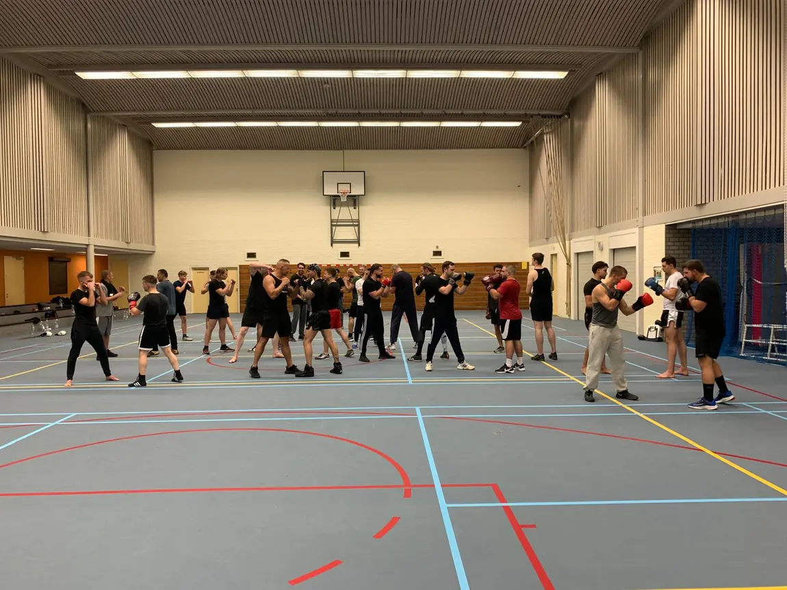 Grote groep deelnemers tijdens een kickboks clinic van Bas van den Muijsenberg in een sportzaal